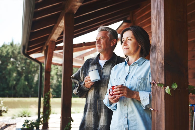 A couple standing on the porch of a country home