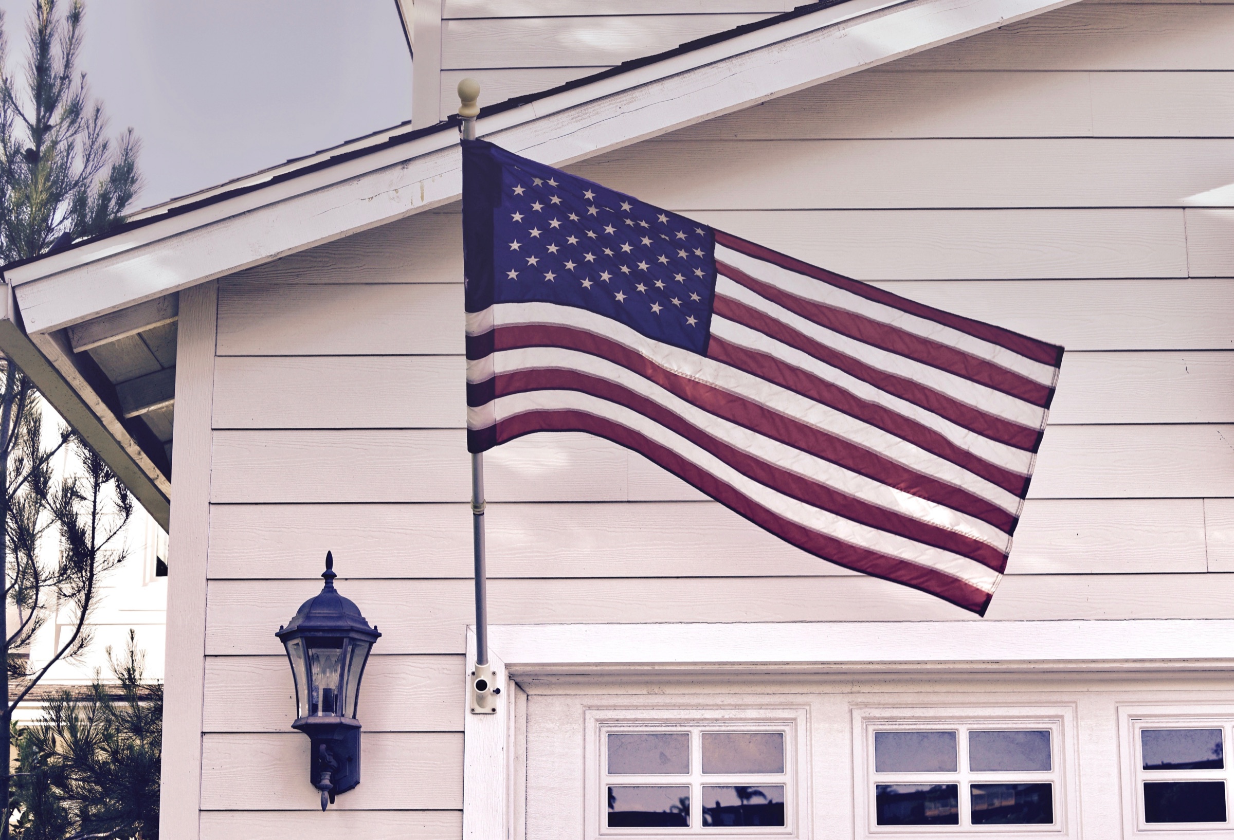 An American flag hanging on the front of a white house