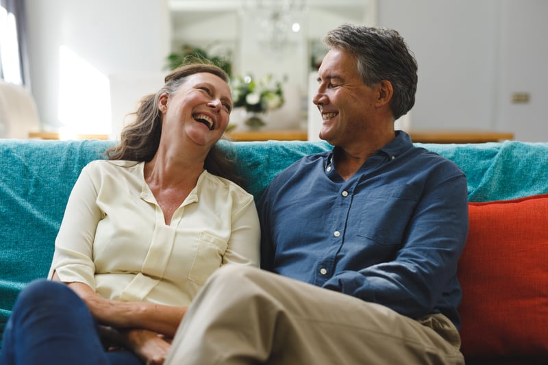 An older couple laughing together on a blue couch