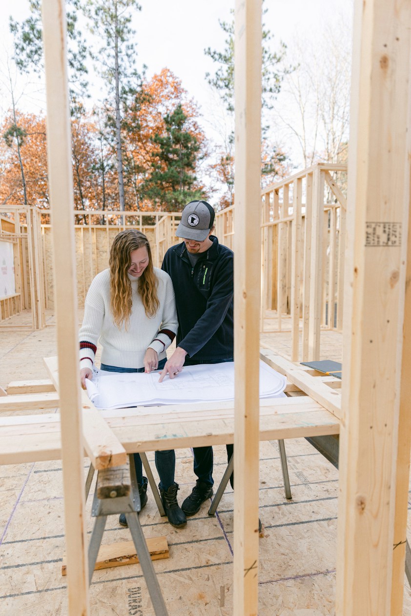 A couple reviewing plans inside the framing of their new home