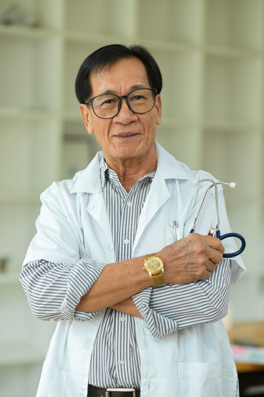 An older doctor in a white coat with his arms crossed