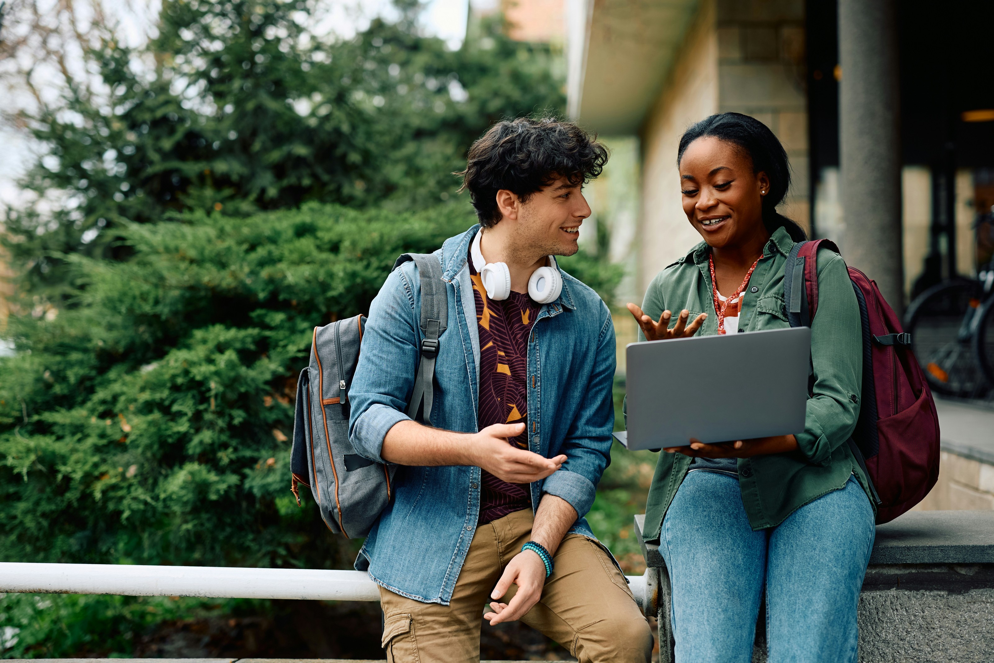 Two medical students talking outdoors with a laptop