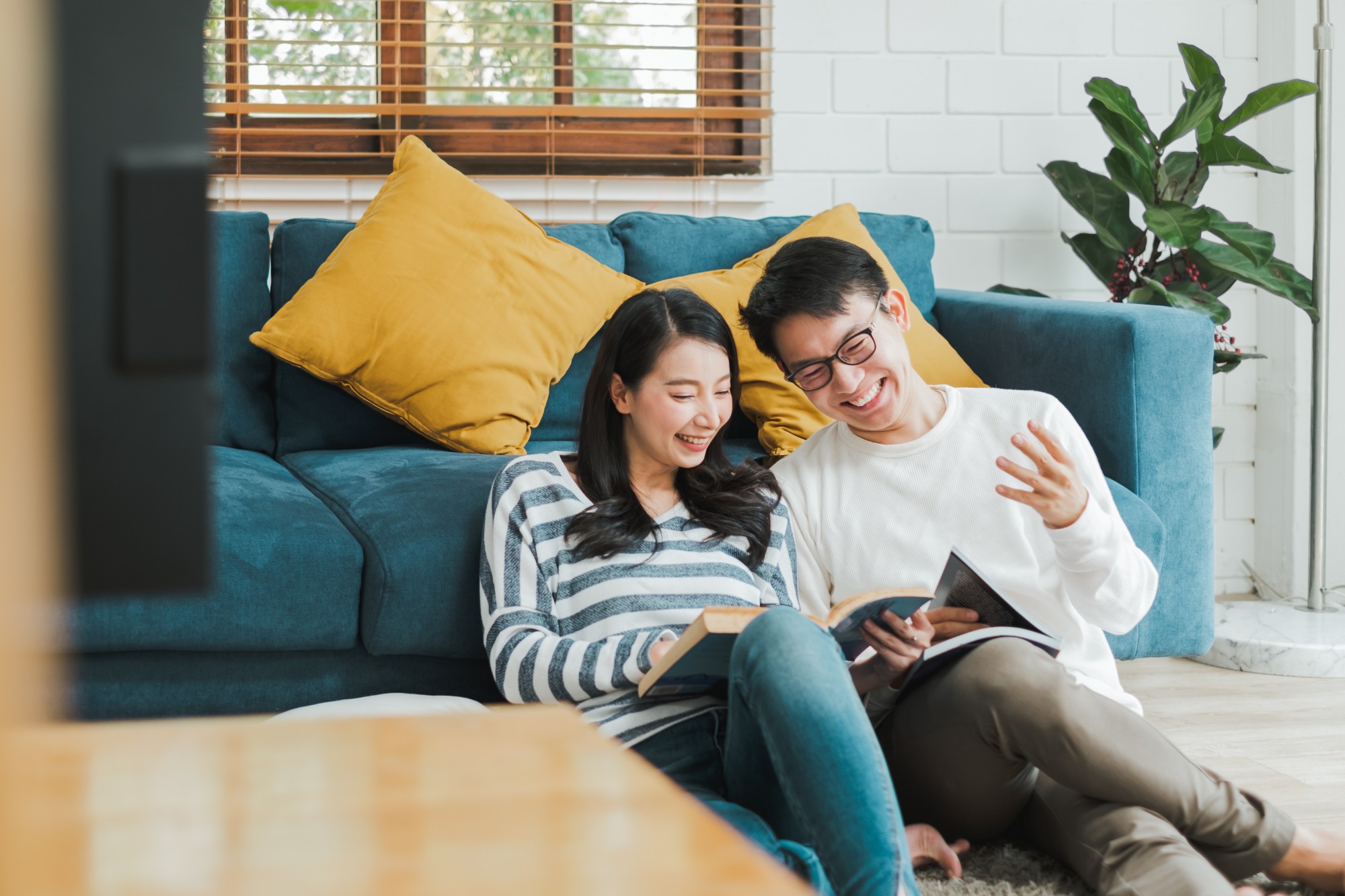 A smiling couple reading together on their living room floor