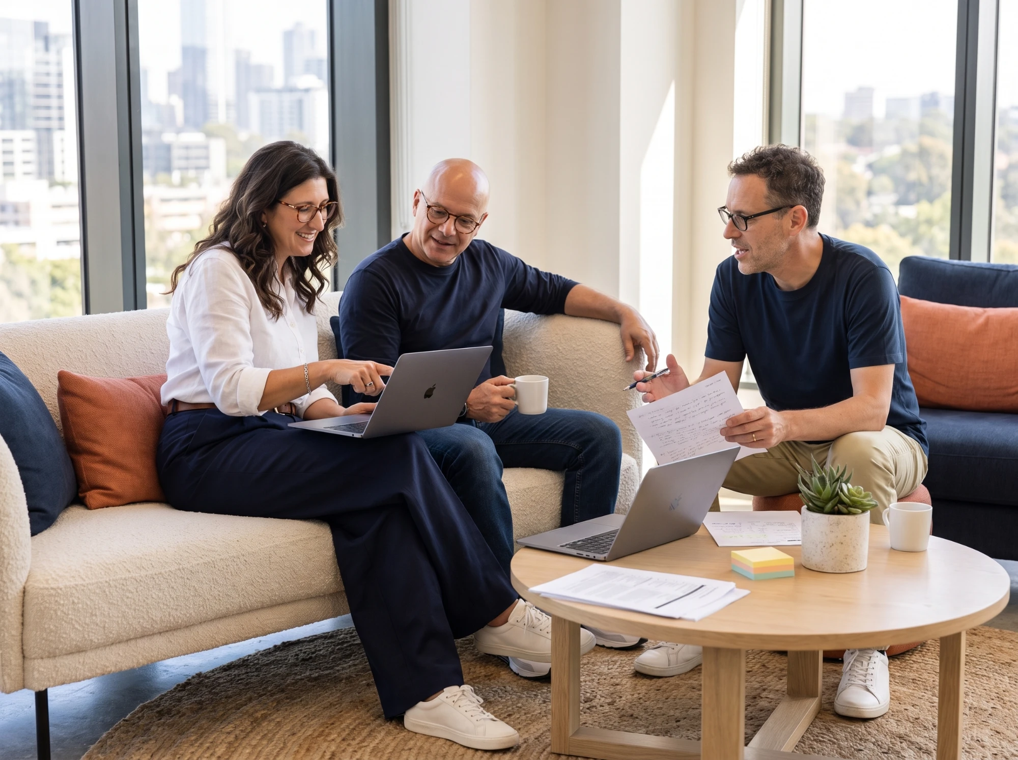 The three Synthrics co-founders working together around a coffee table with laptops and notes