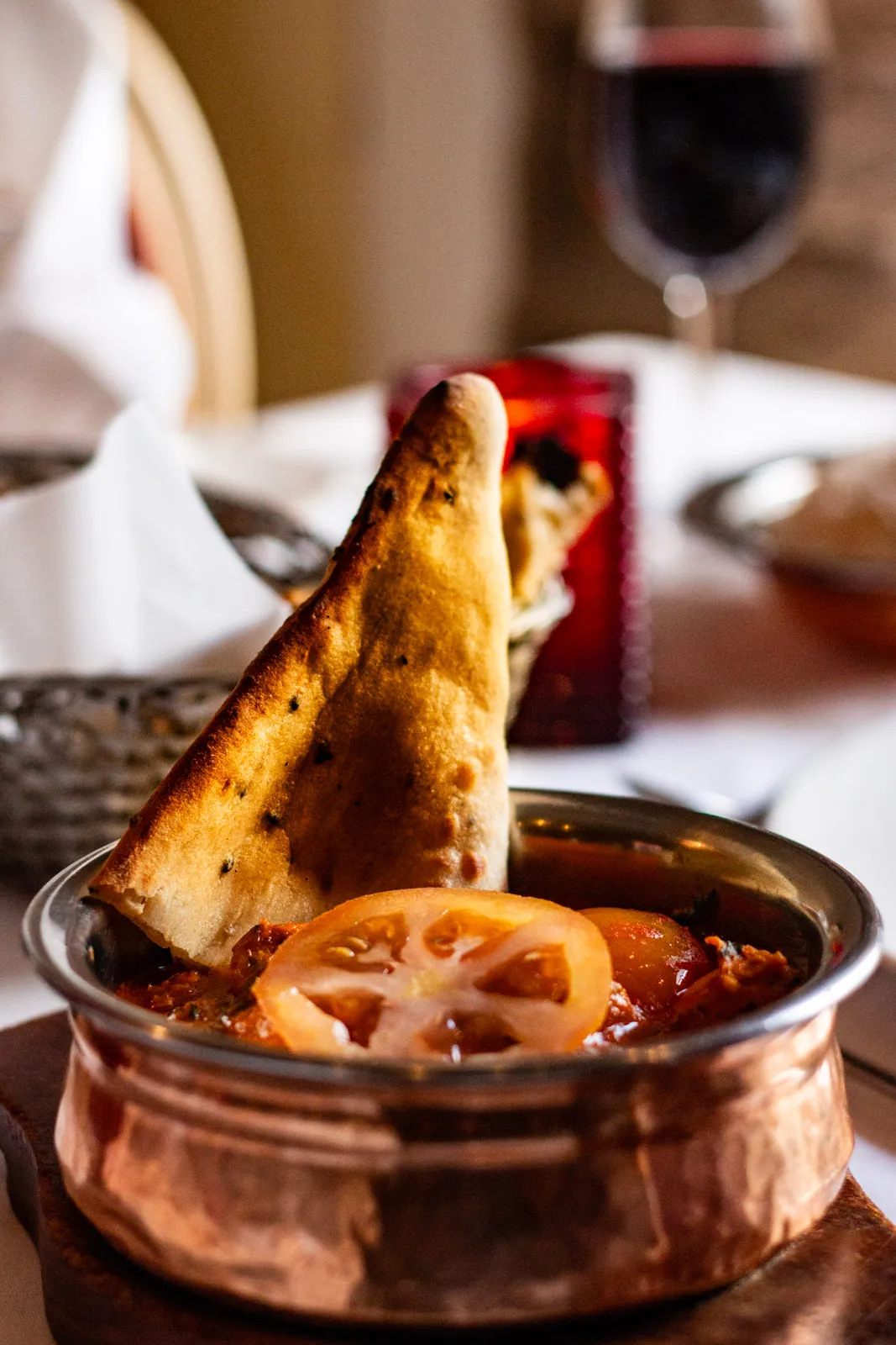 Curry served in a copper handi with naan bread