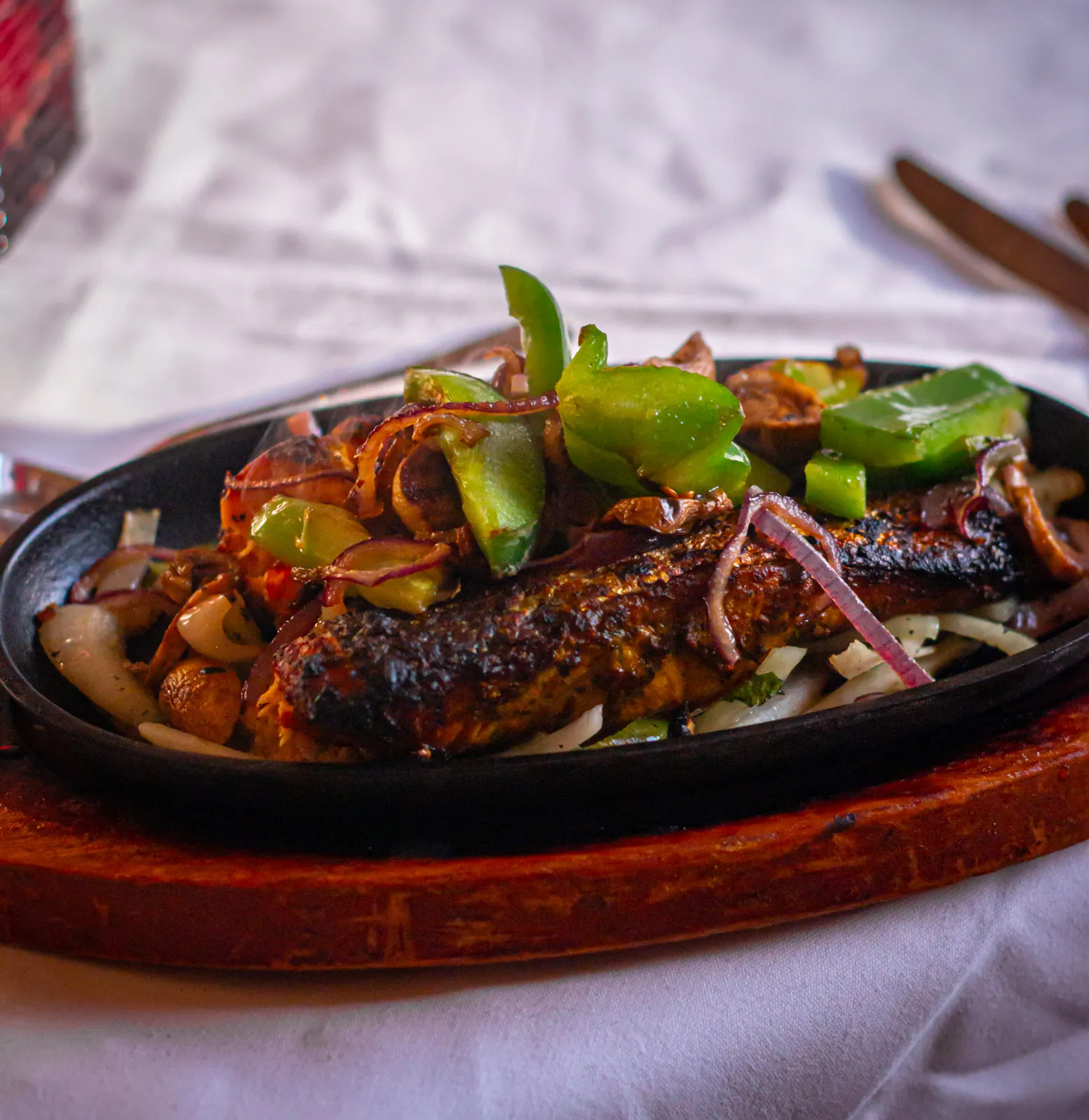 Grilled sizzler with peppers, onions and mushrooms on a cast-iron plate