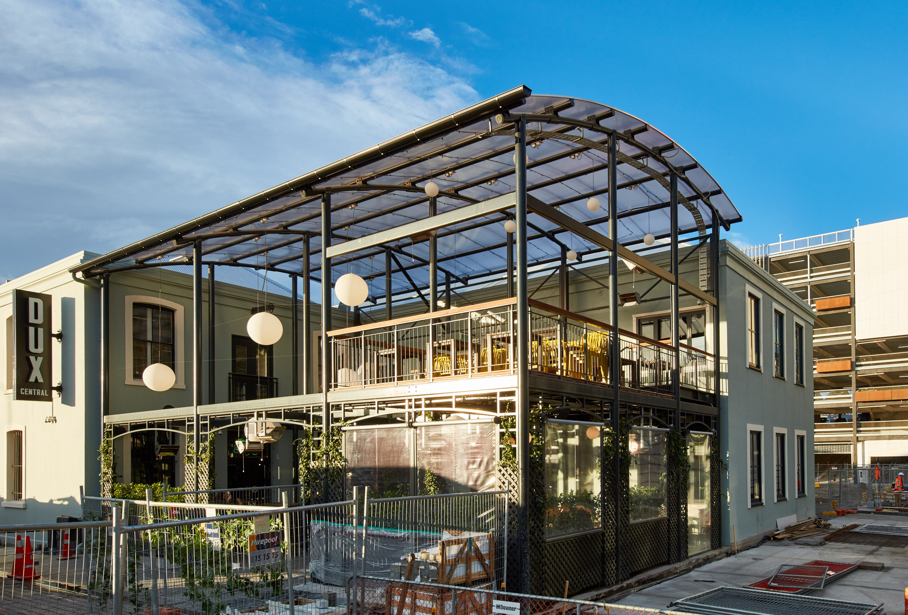 Two-story building with a glass-covered outdoor seating area and DUX Central sign on the side.