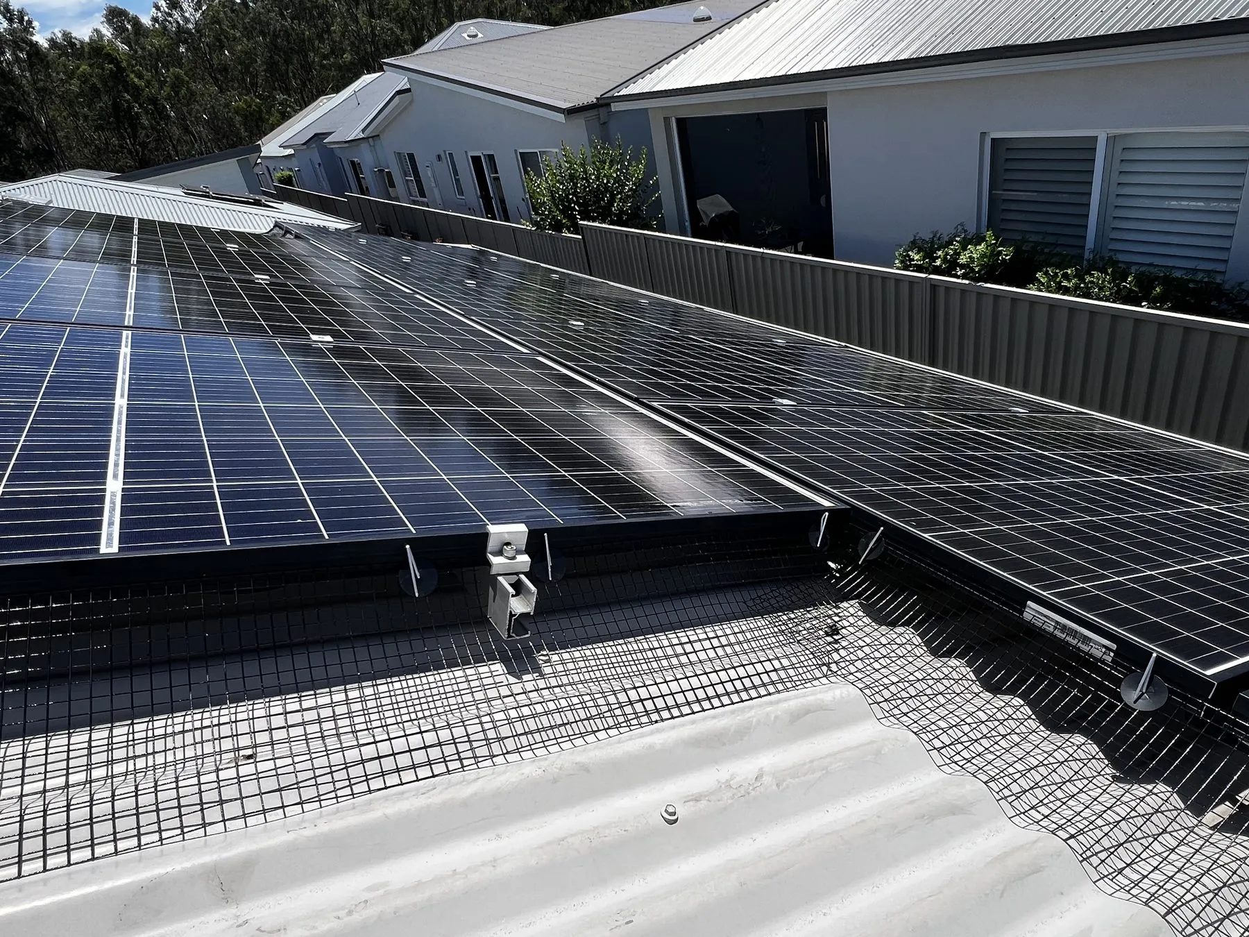Mesh barrier fitted around solar panels on a metal roof