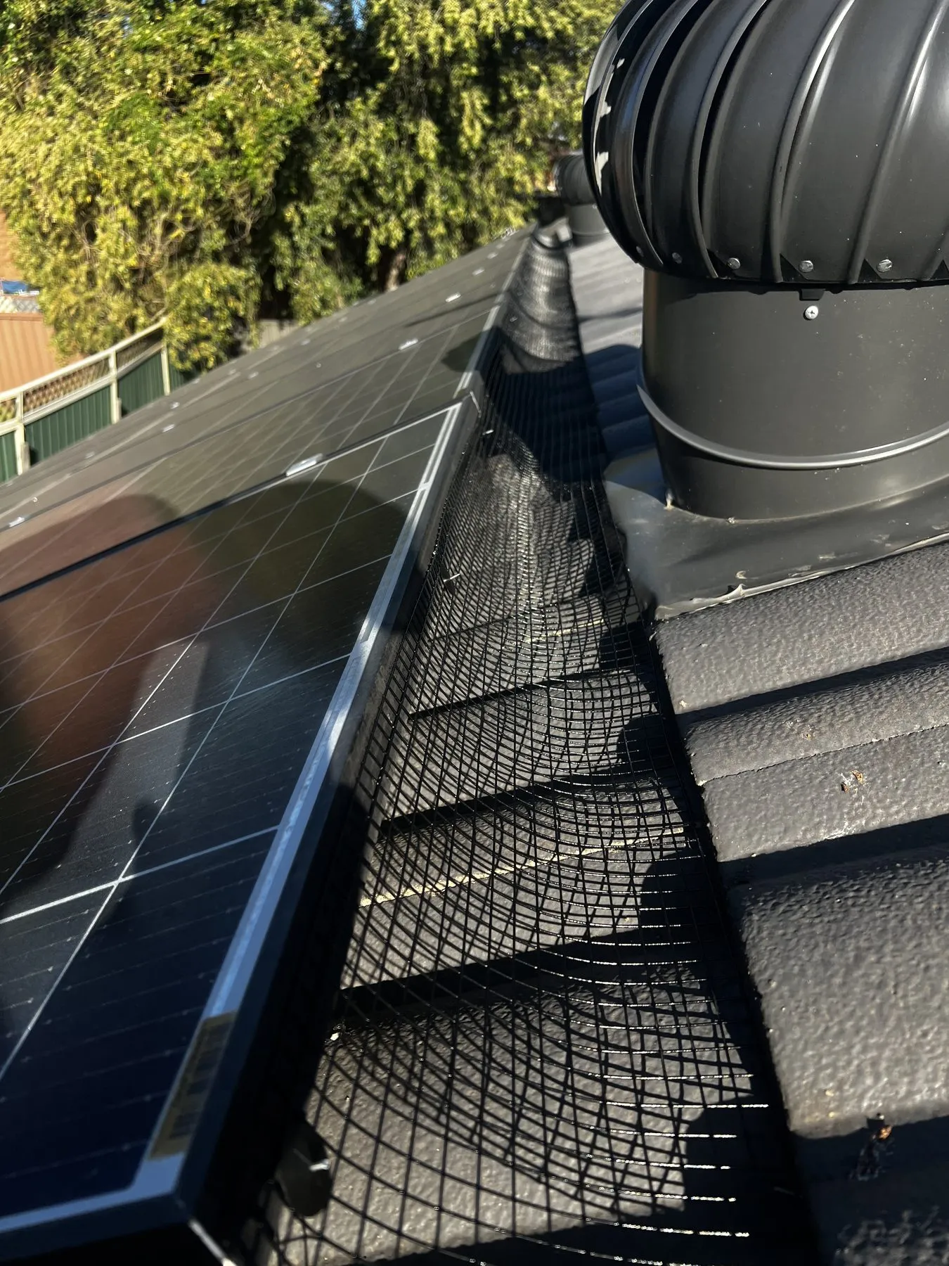 Close-up of bird mesh beneath the edge of a solar panel
