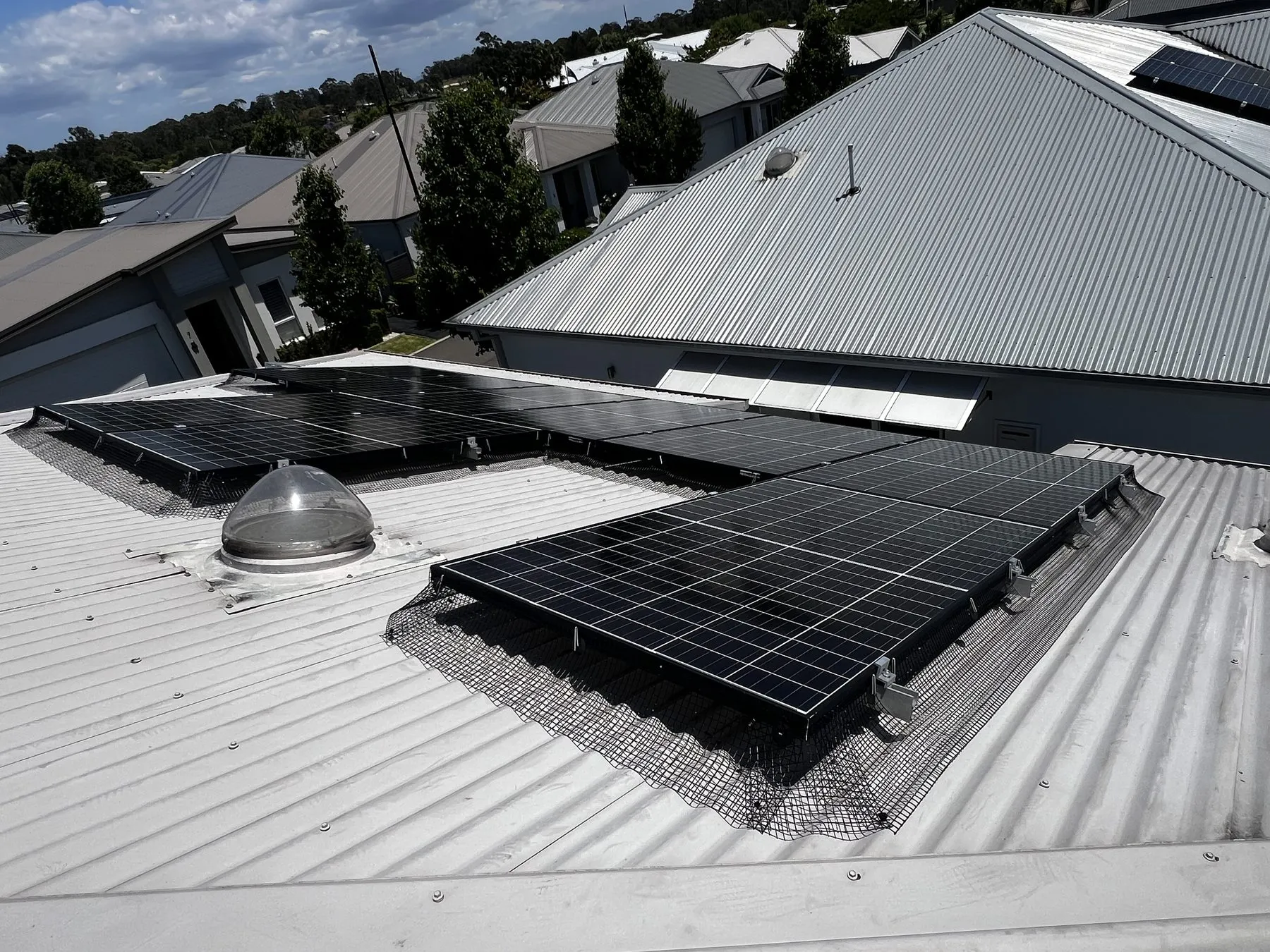Solar bird-mesh installation viewed across a metal roof