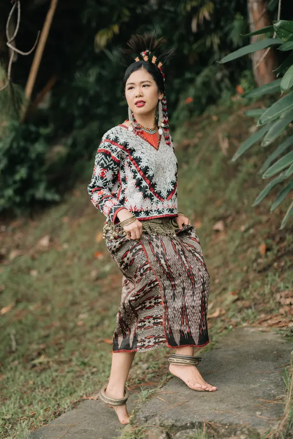 Cecille in Tboli dress and a feathered headdress, on a hillside path