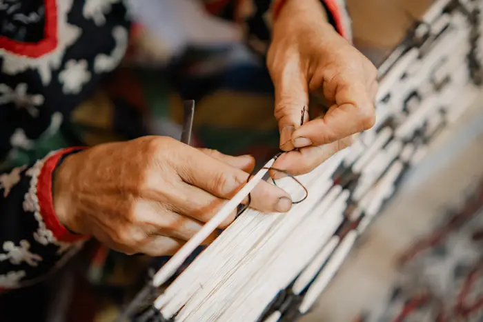 Hands tying the pattern into the warp