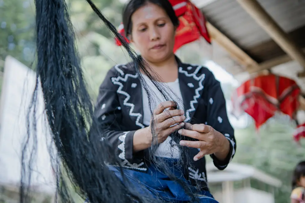 A weaver tying bundles of dyed abaca fibre