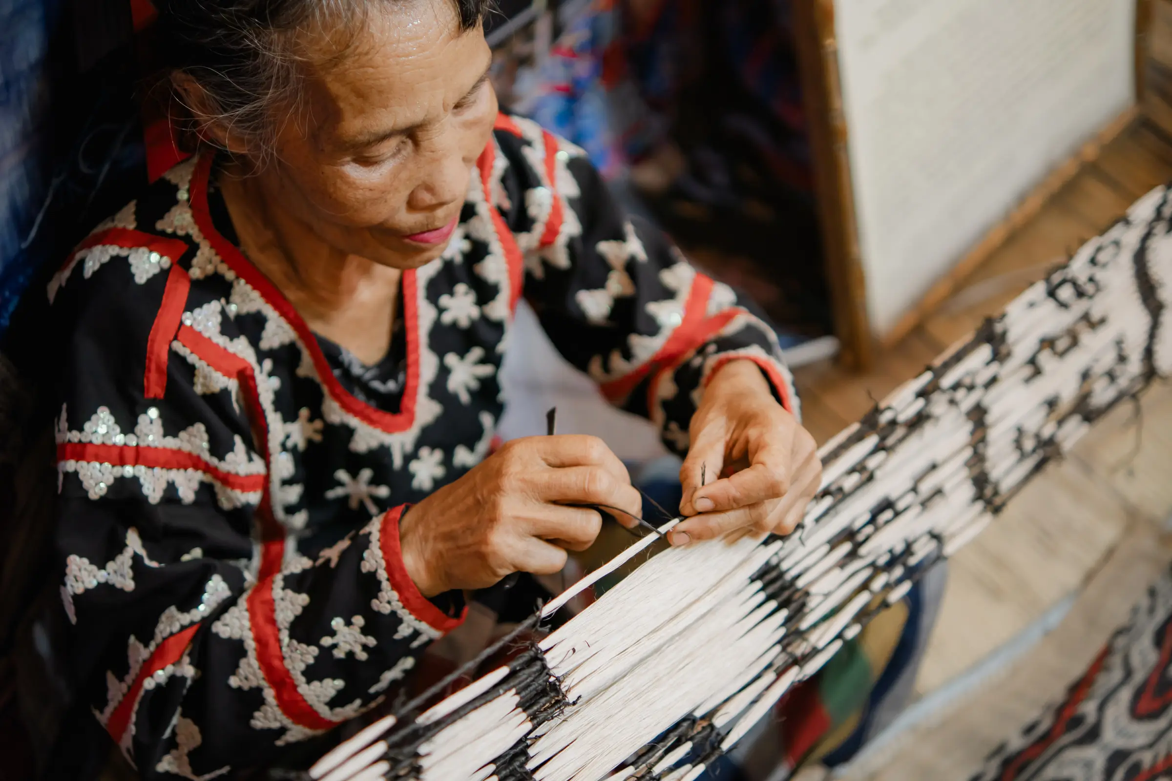 A weaver’s hands at the loom, working white abaca threads