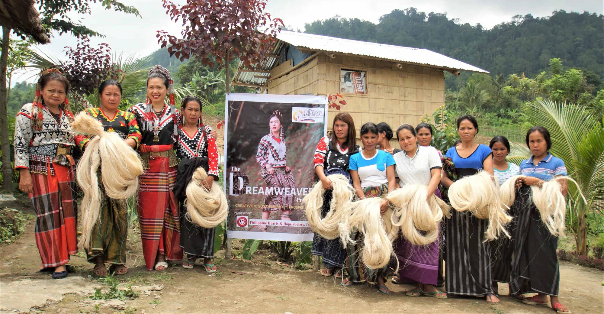 A group of women in Tboli dress holding bundles of abaca fibre beside a Dreamweaver Project banner