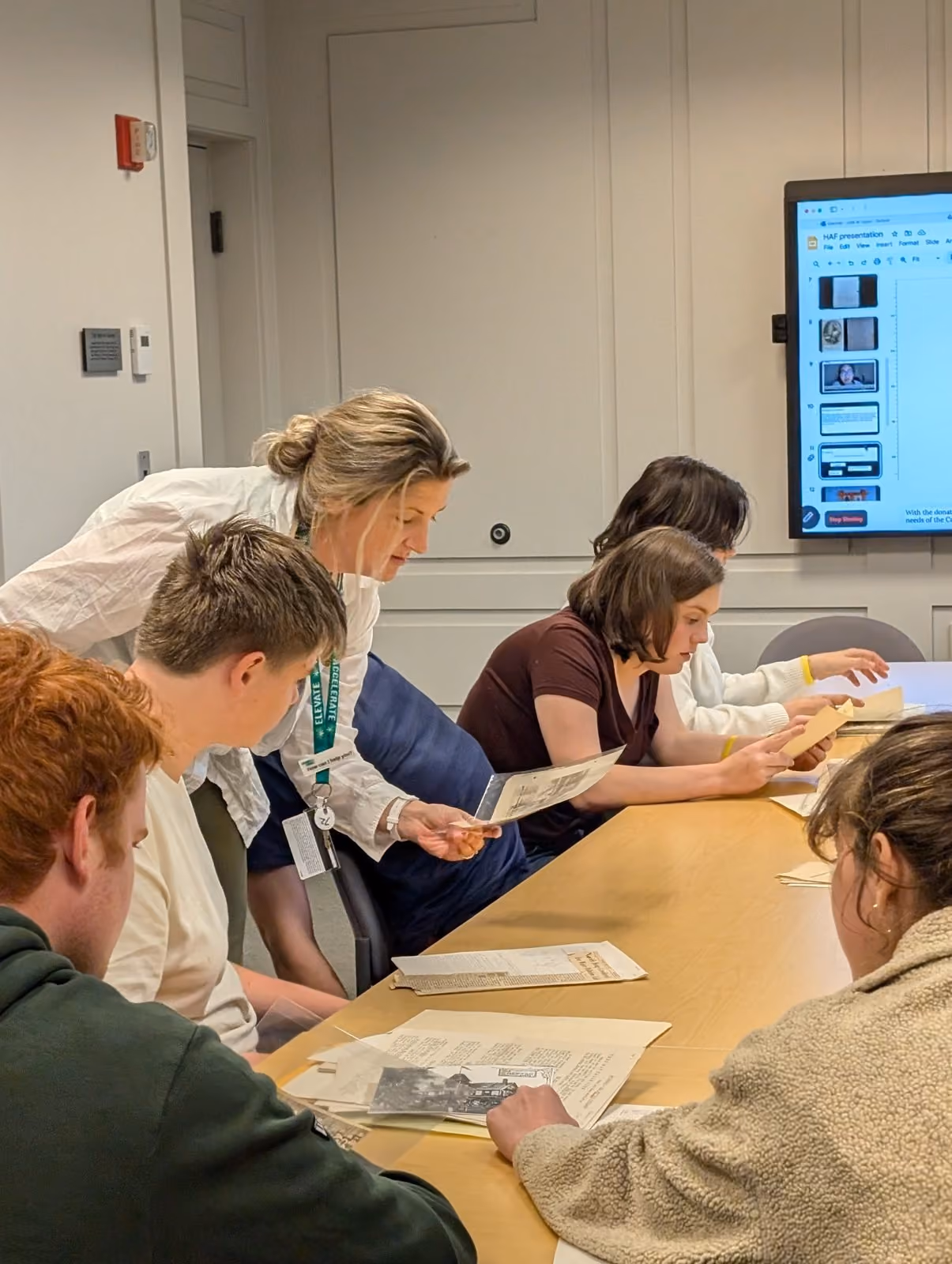 A staff member guiding students through archival documents
