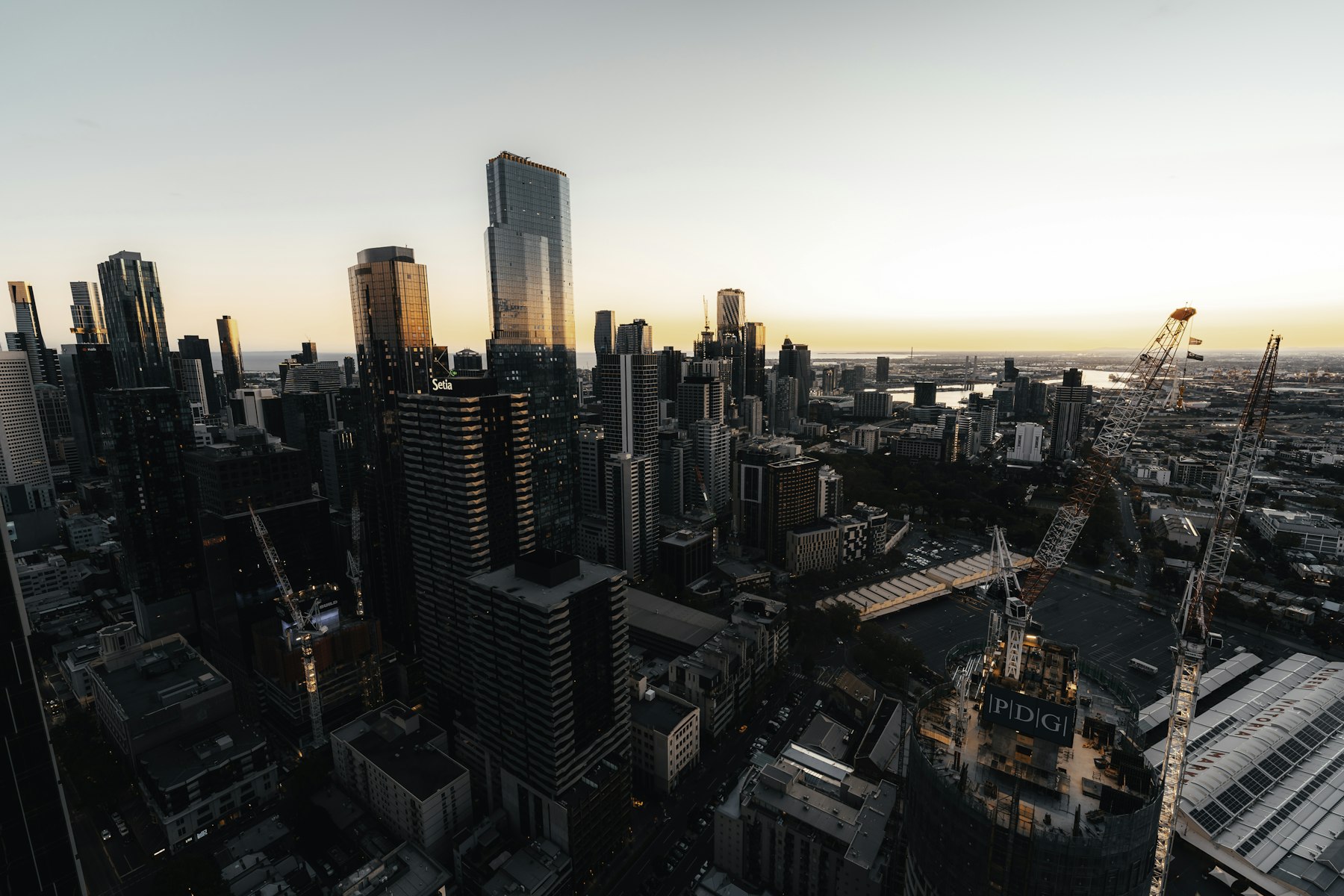 Melbourne city skyline at dusk with tower cranes over buildings under construction