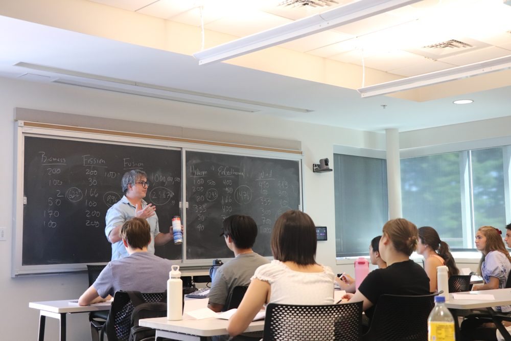 An instructor at a chalkboard comparing energy sources