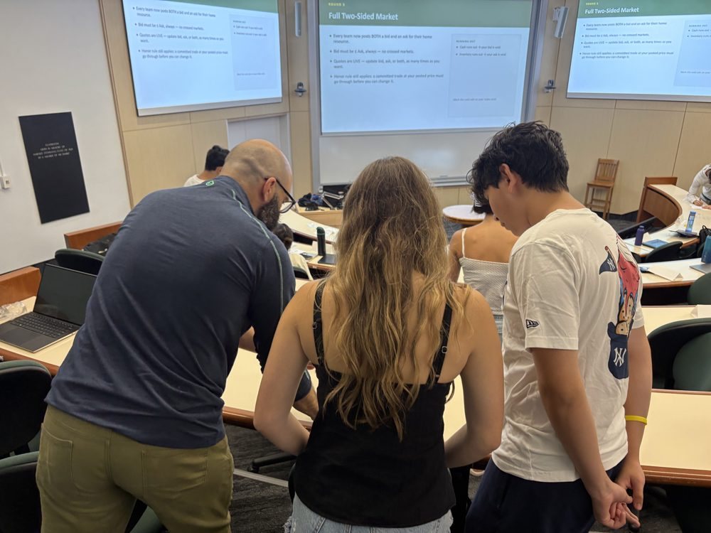 An instructor working with students during a market trading simulation