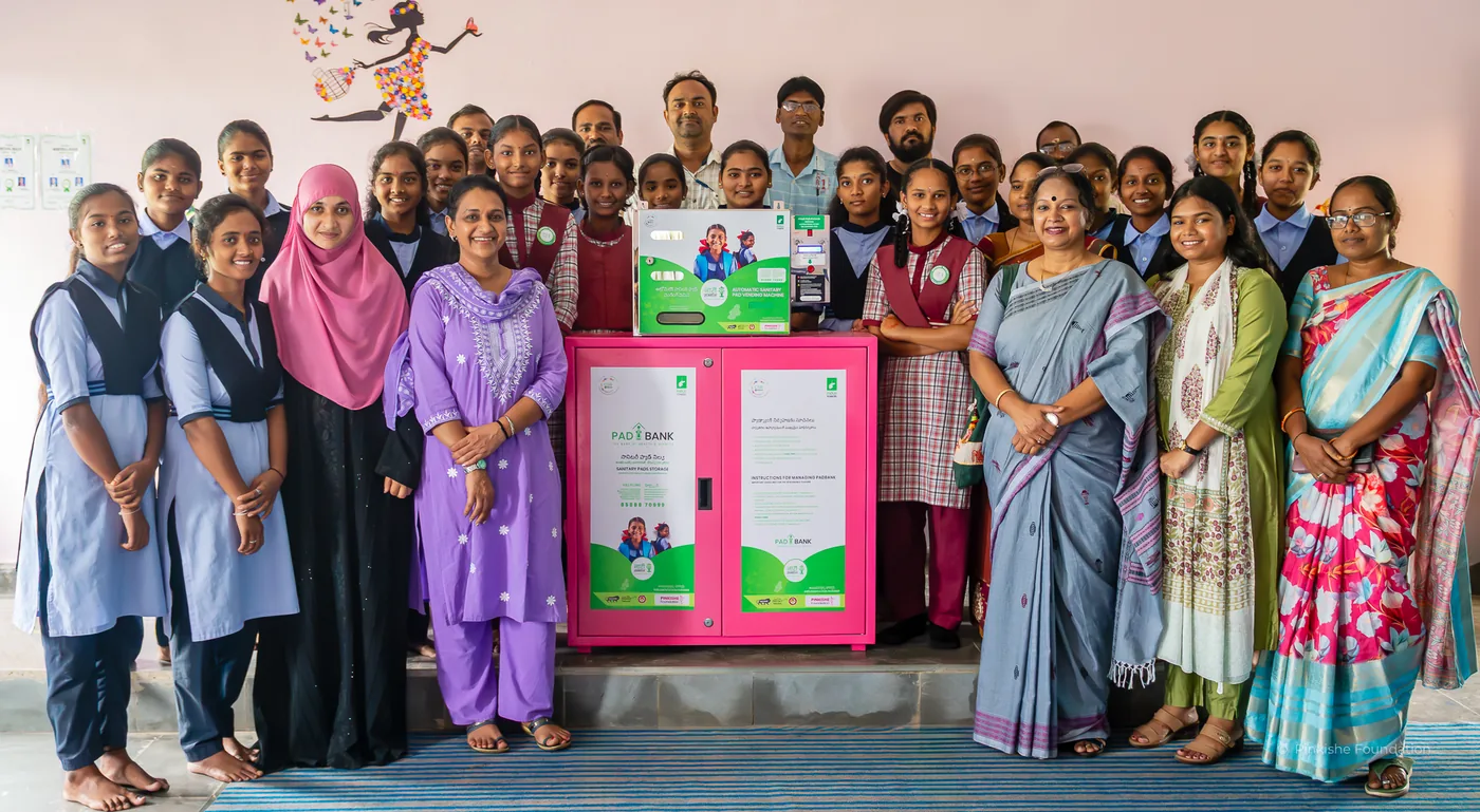 Schoolgirls and teachers gathered around their school's pad vending unit in Telangana