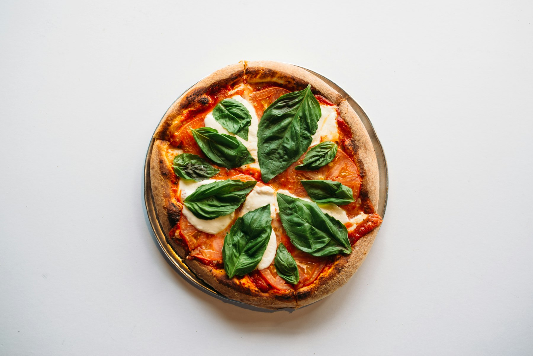 Een hele Margherita van bovenaf, met tomatensaus, gesmolten mozzarella en verse basilicum