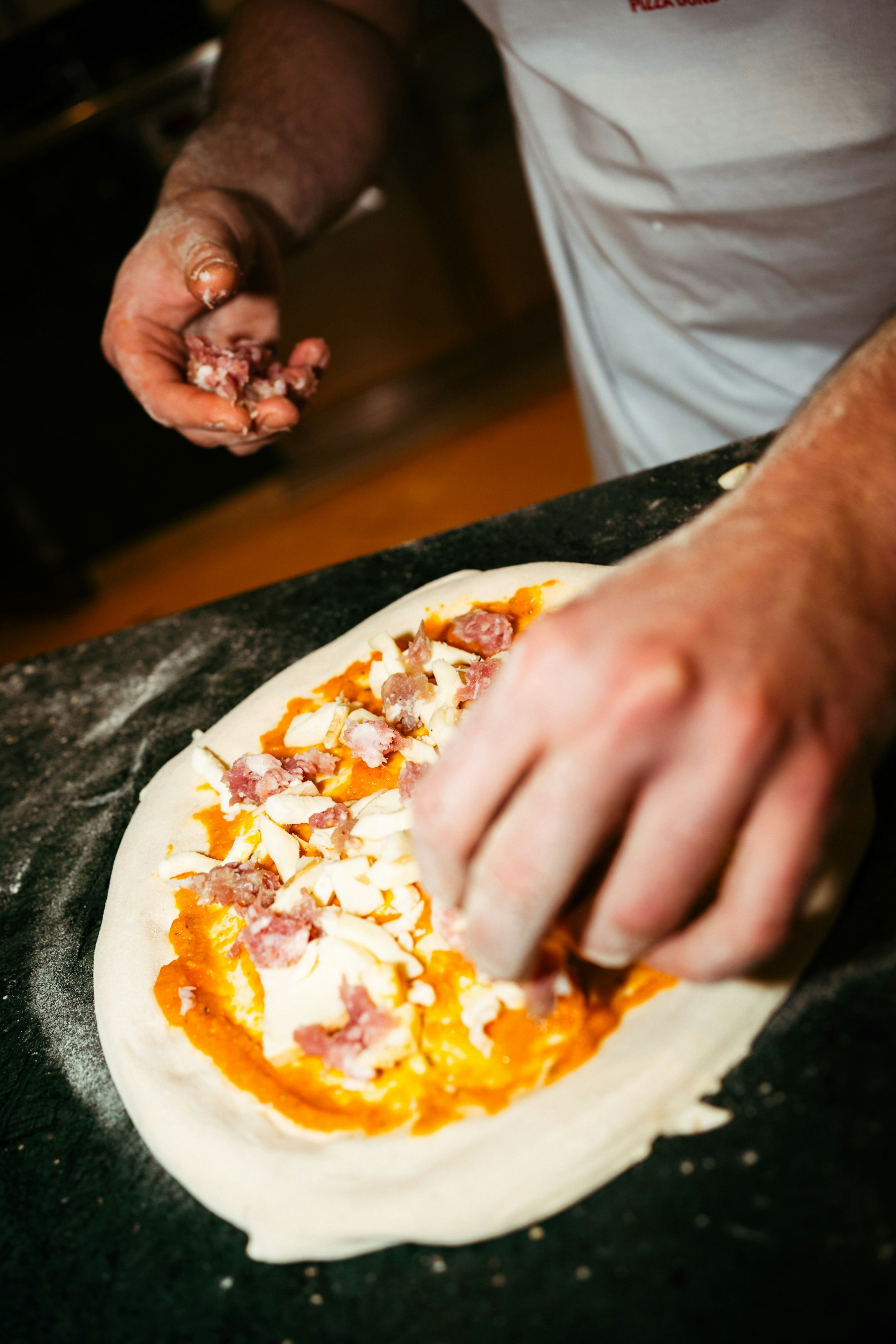 Handen die een pizza beleggen