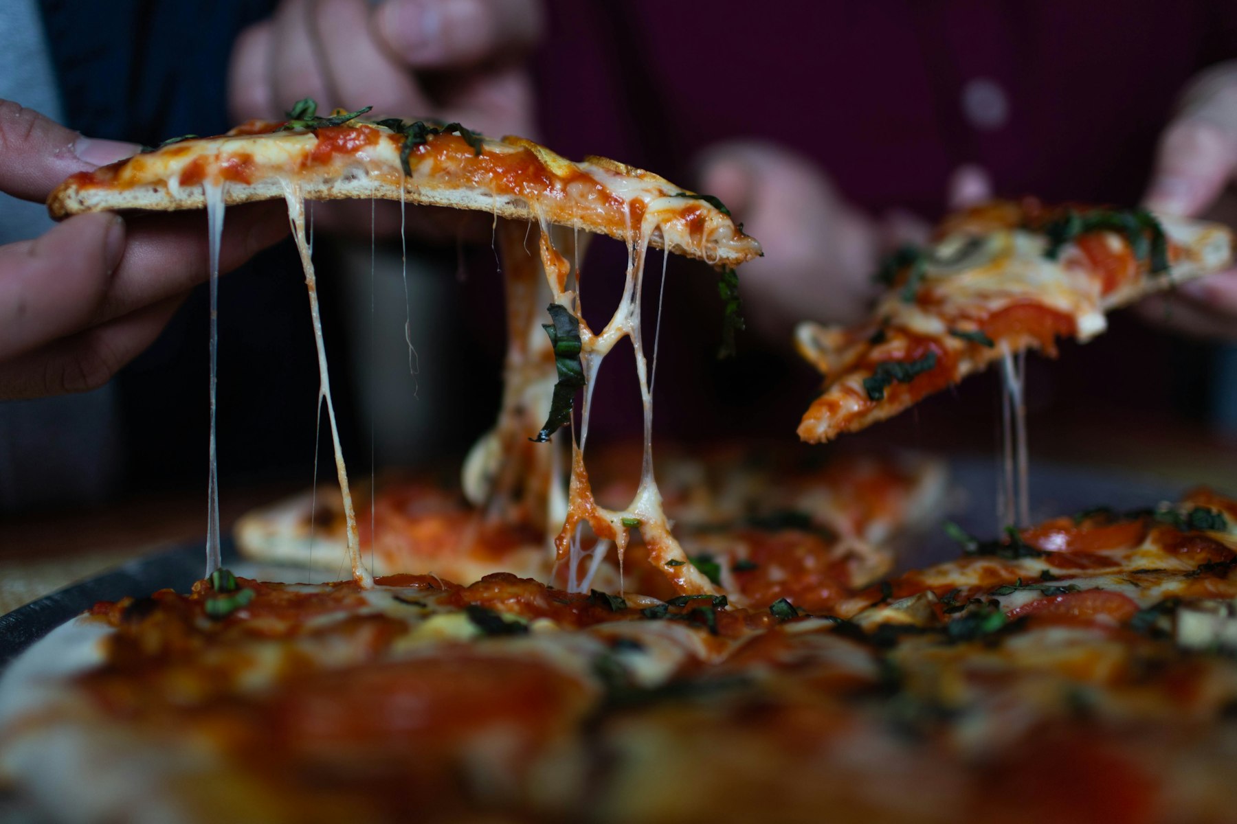 Vrienden aan tafel die punten pizza van een gedeelde plank pakken