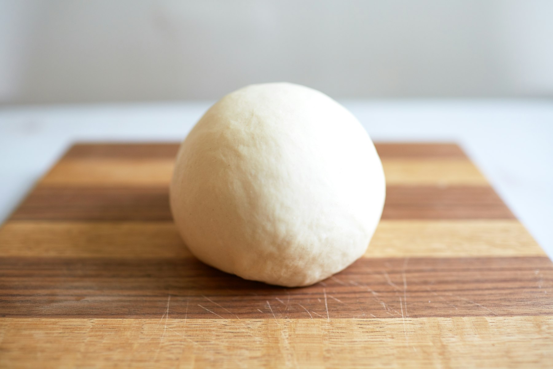 Bal pizzadeeg met bloem op een houten werkblad