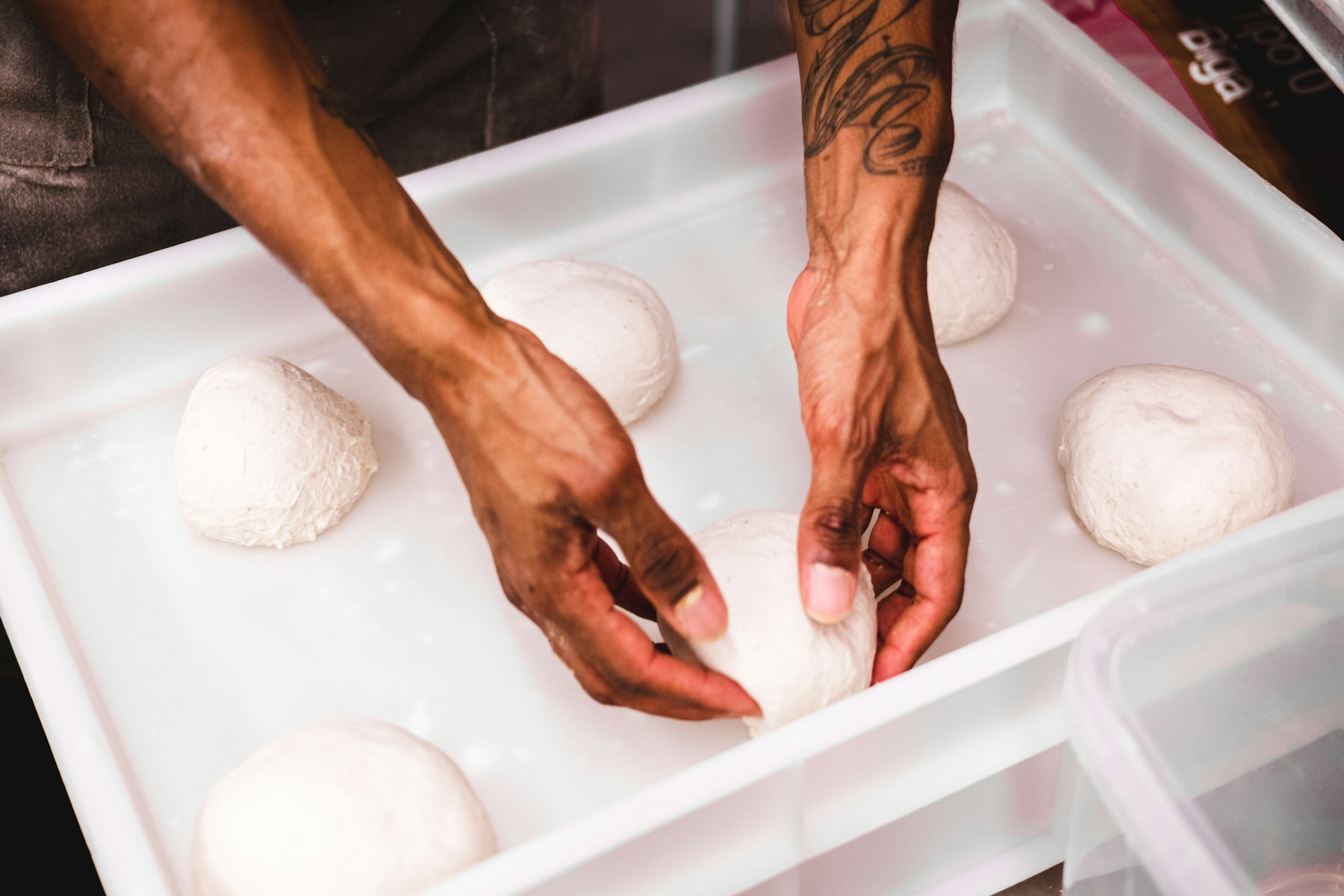 Ronde bollen pizzadeeg die rustig rijzen in een bak