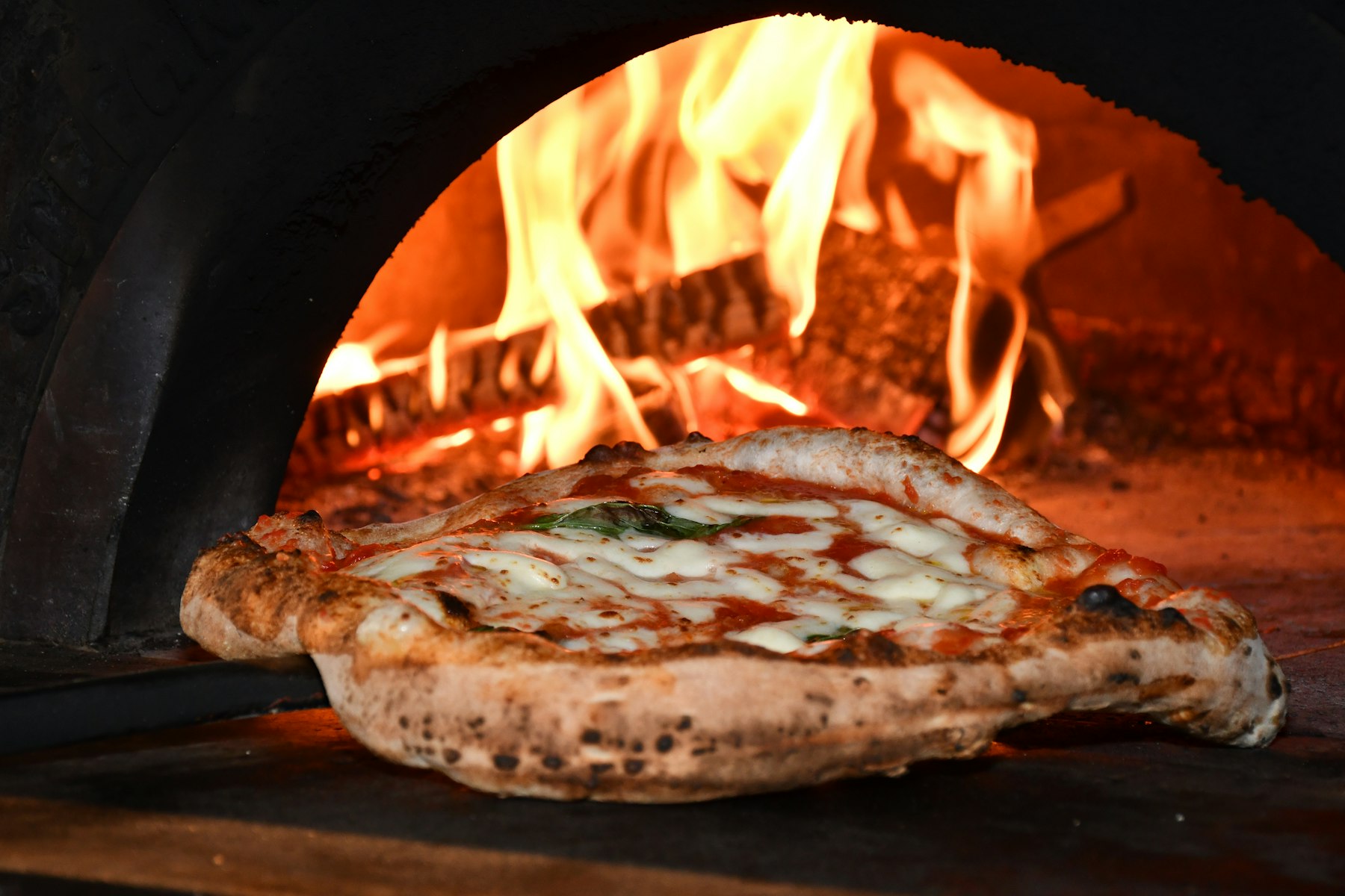 Handen met bloem die een bal pizzadeeg vormen op een houten werkblad