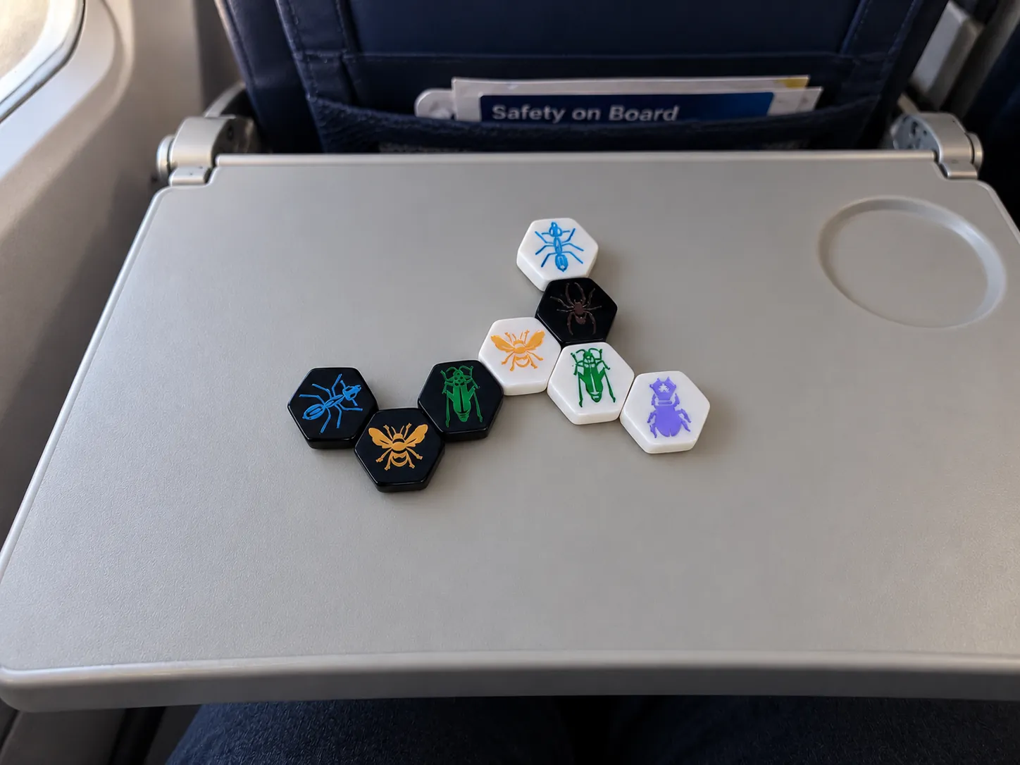 Hive Pocket game tiles set out on an aeroplane-sized tray table