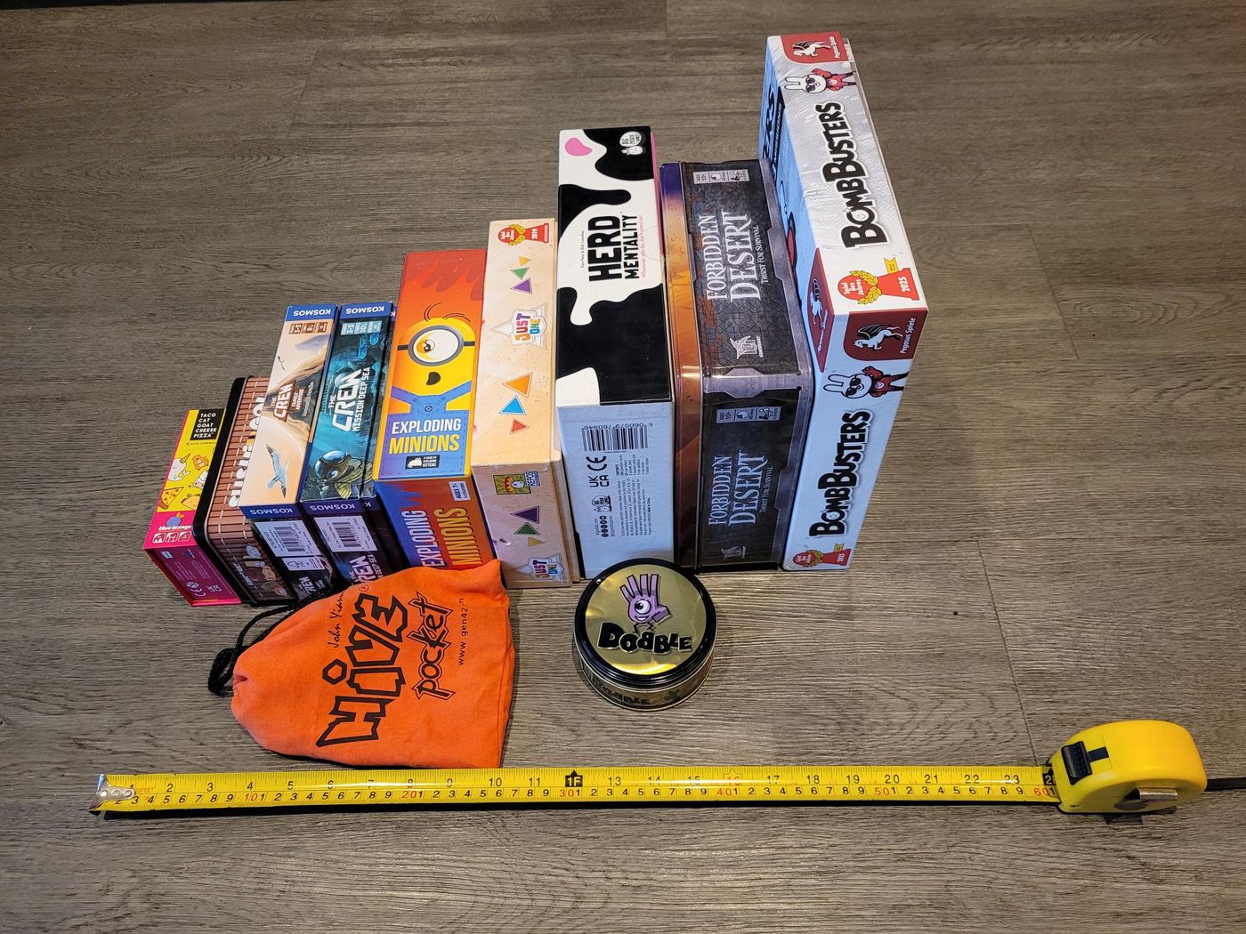Travel game boxes stacked from smallest to largest next to a tape measure