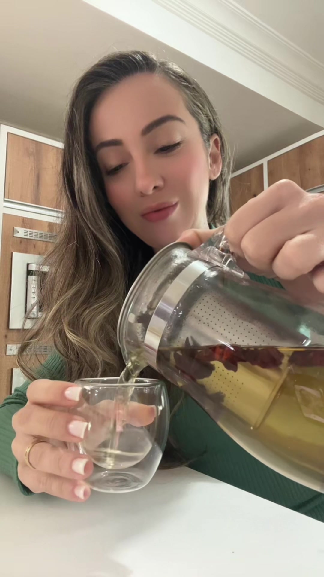 Flávia servindo chá em um bule de vidro com infusor, num vídeo do TikTok