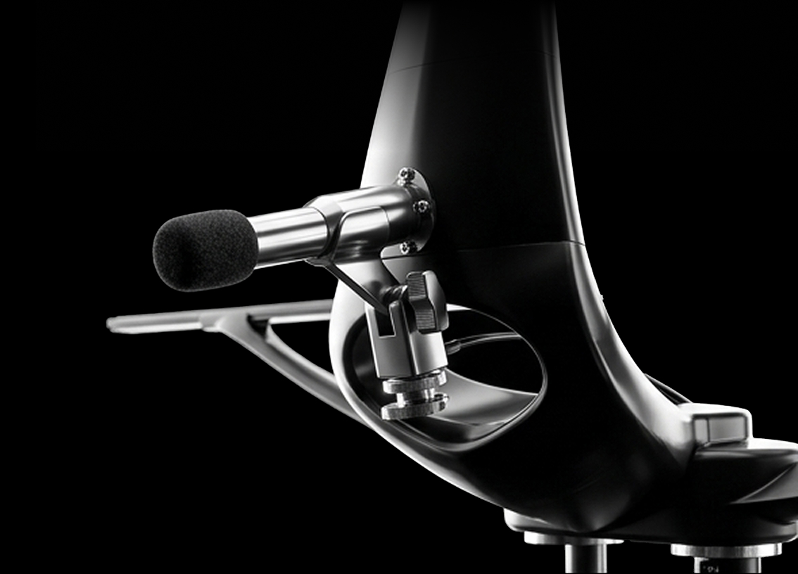 Close-up of a sleek black multimedia stand featuring a silver microphone with a foam windscreen attached to a mounting bracket.