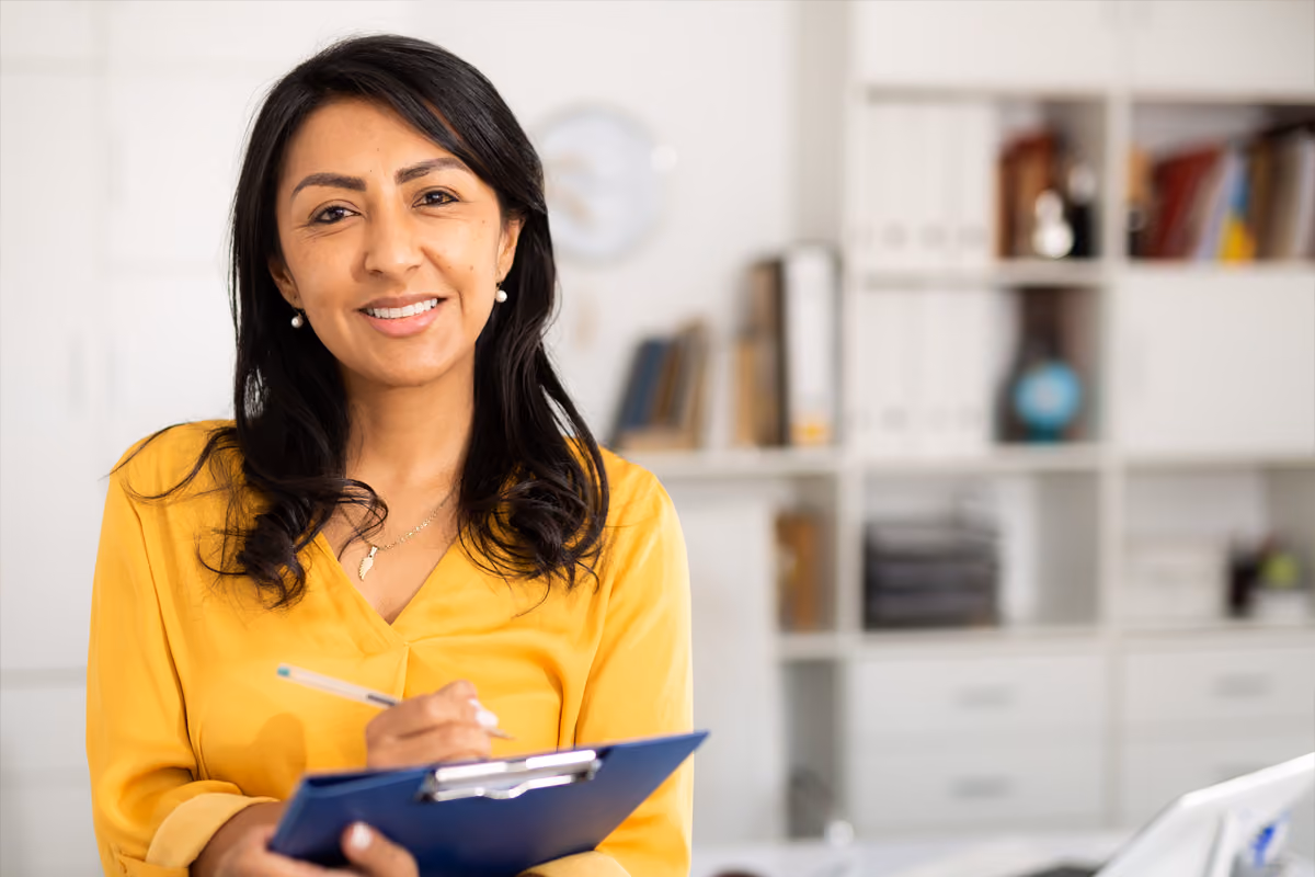 Smiling professional holding a clipboard in a bright office