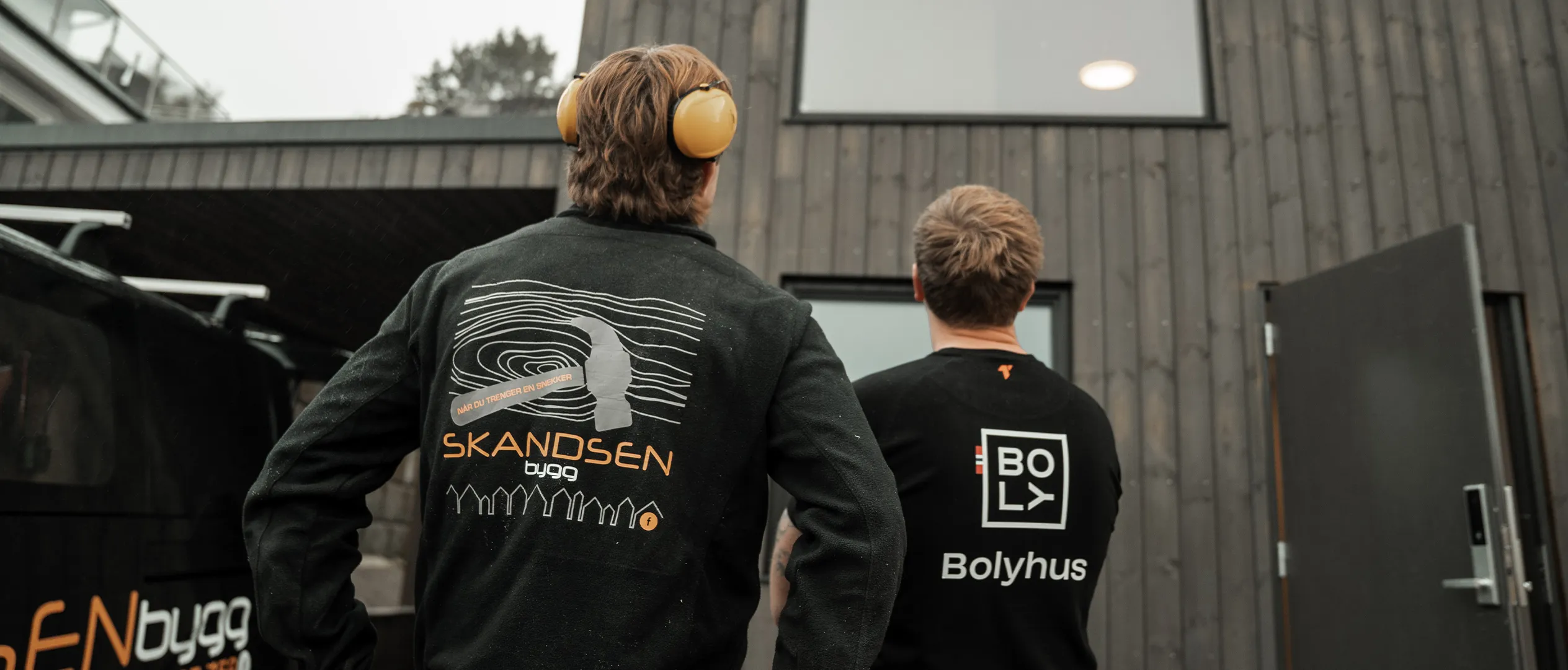Tre fra Skandsen Bygg foran en hytte under bygging ved sjøen