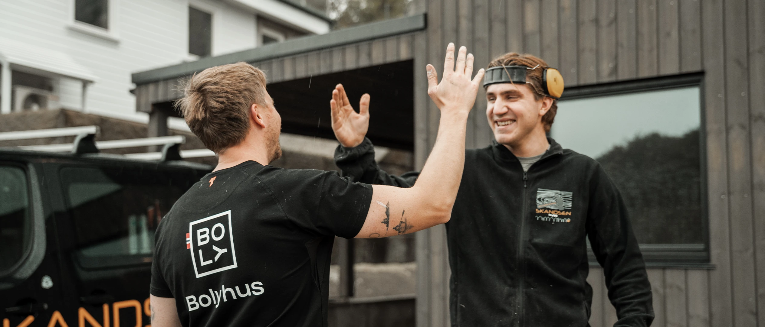 To fra Skandsen Bygg gir hverandre high five, den ene i Bolyhus-t-skjorte