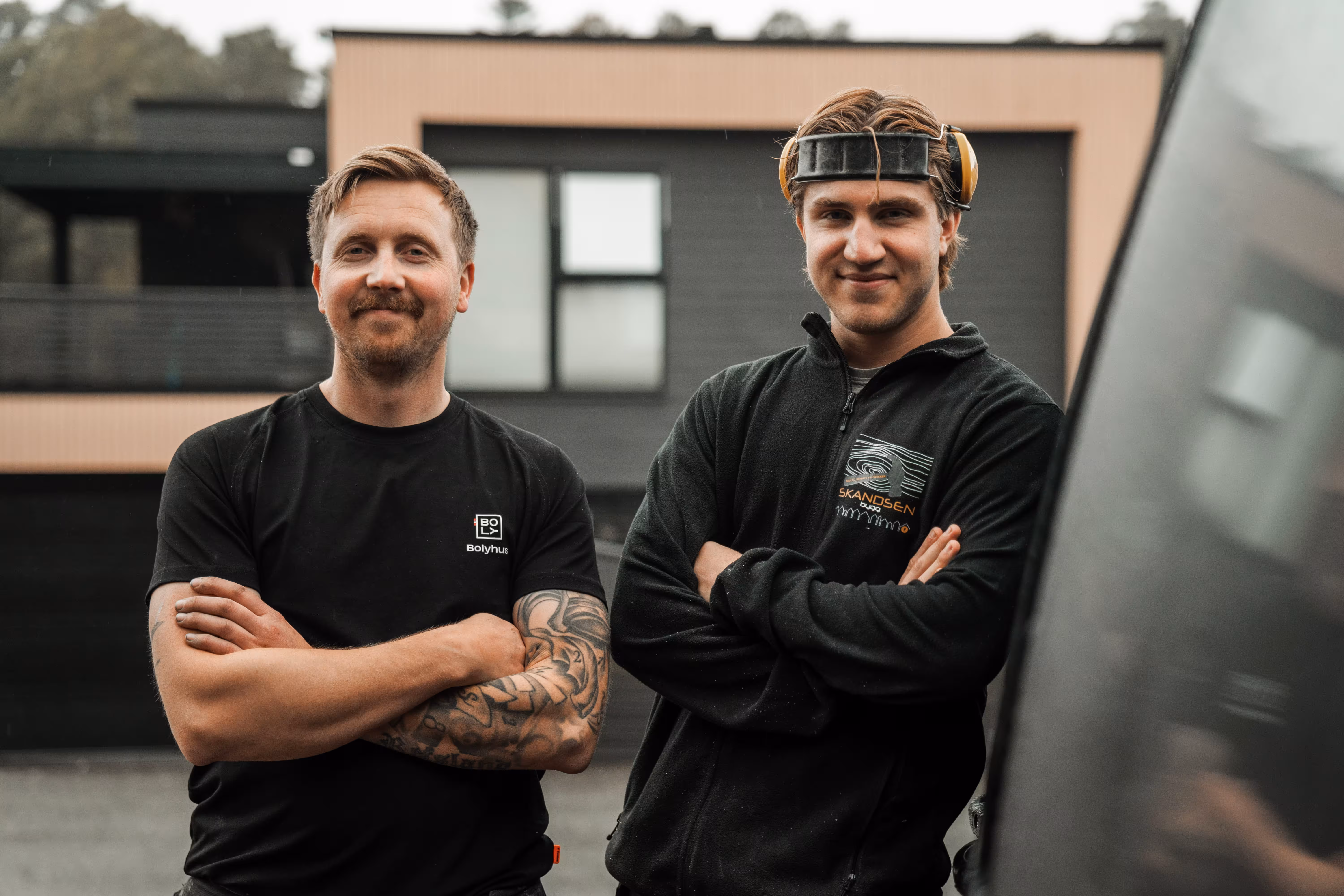 To ansatte fra Skandsen Bygg foran et nytt bygg