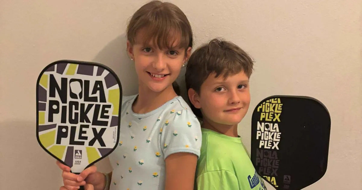 Two kids holding NOLA PicklePlex paddles at kids pickleball camp in New Orleans