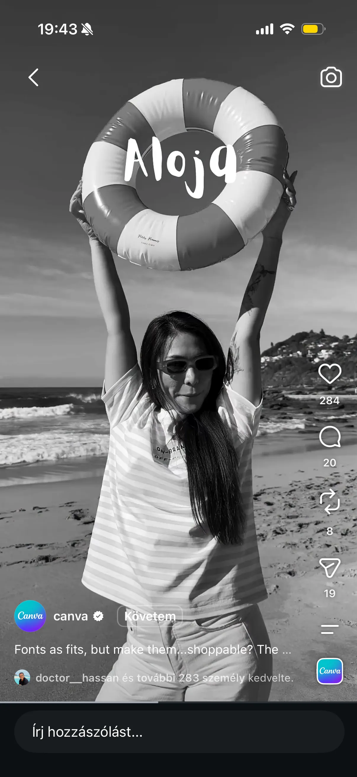 Black-and-white beach shot: a woman holding up an inflatable ring