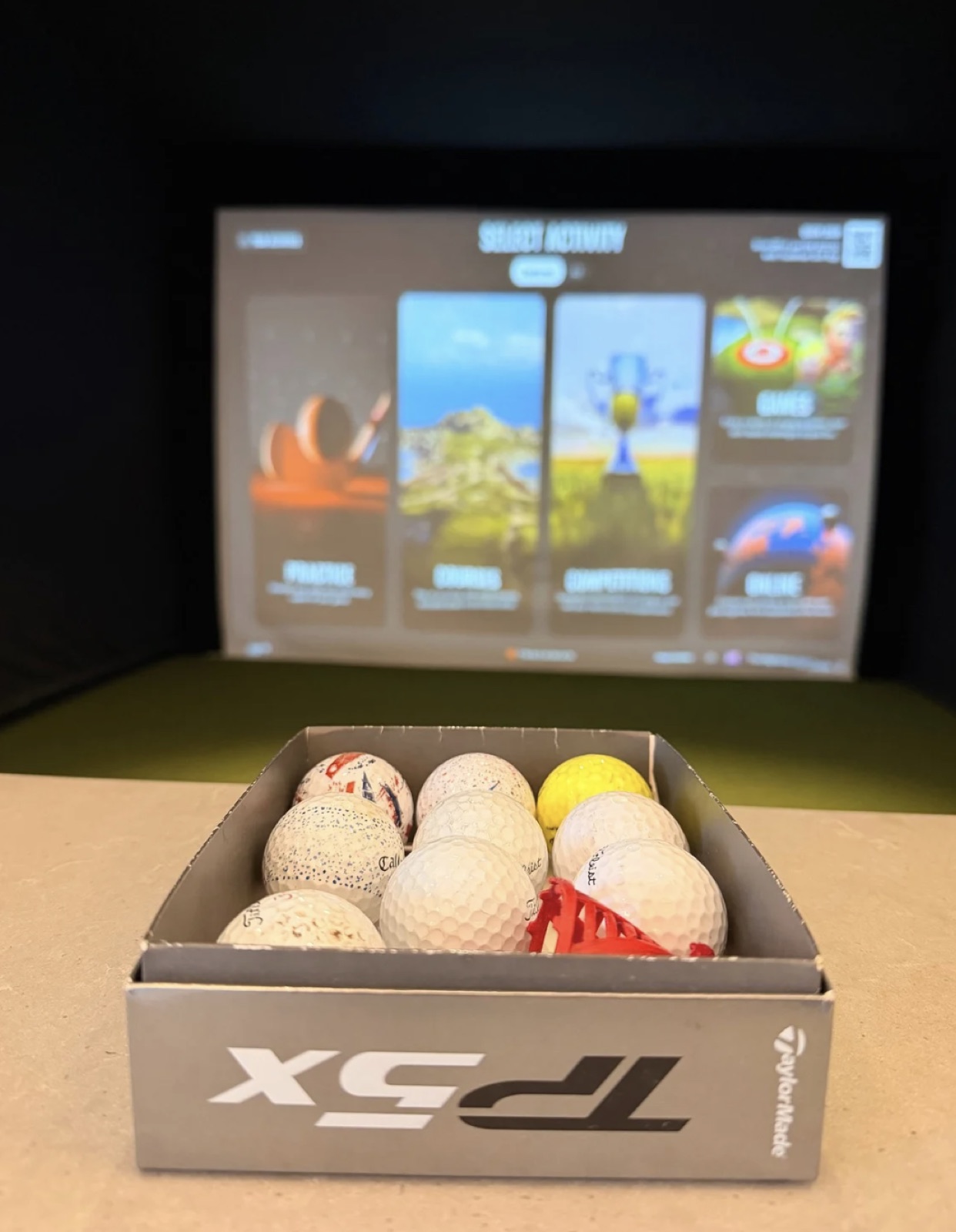TrackMan golf simulator bay with game menu and golf balls at The Highlands in Post Falls, Idaho
