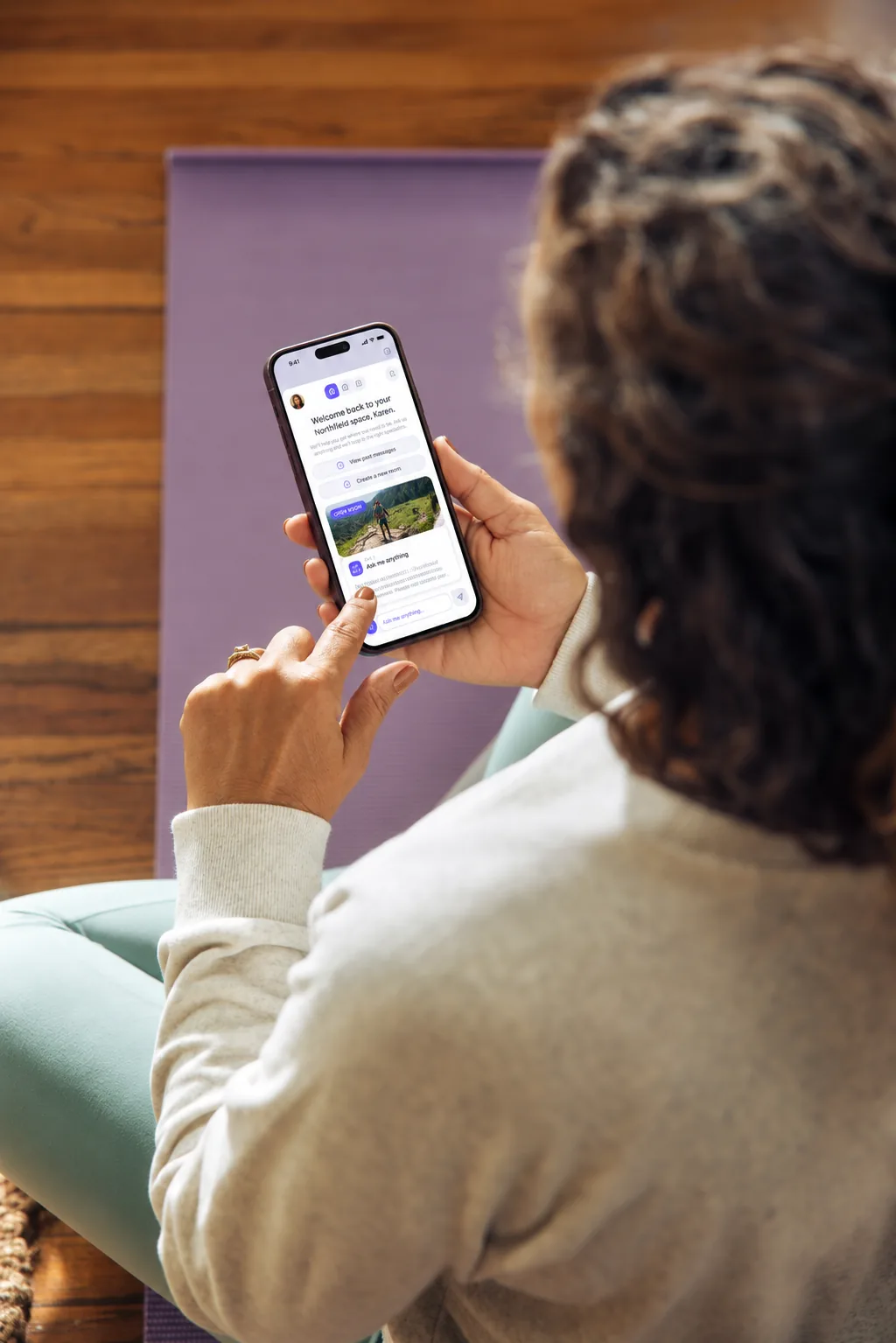 A woman sitting on a yoga mat opening her Zingly Room on a smartphone