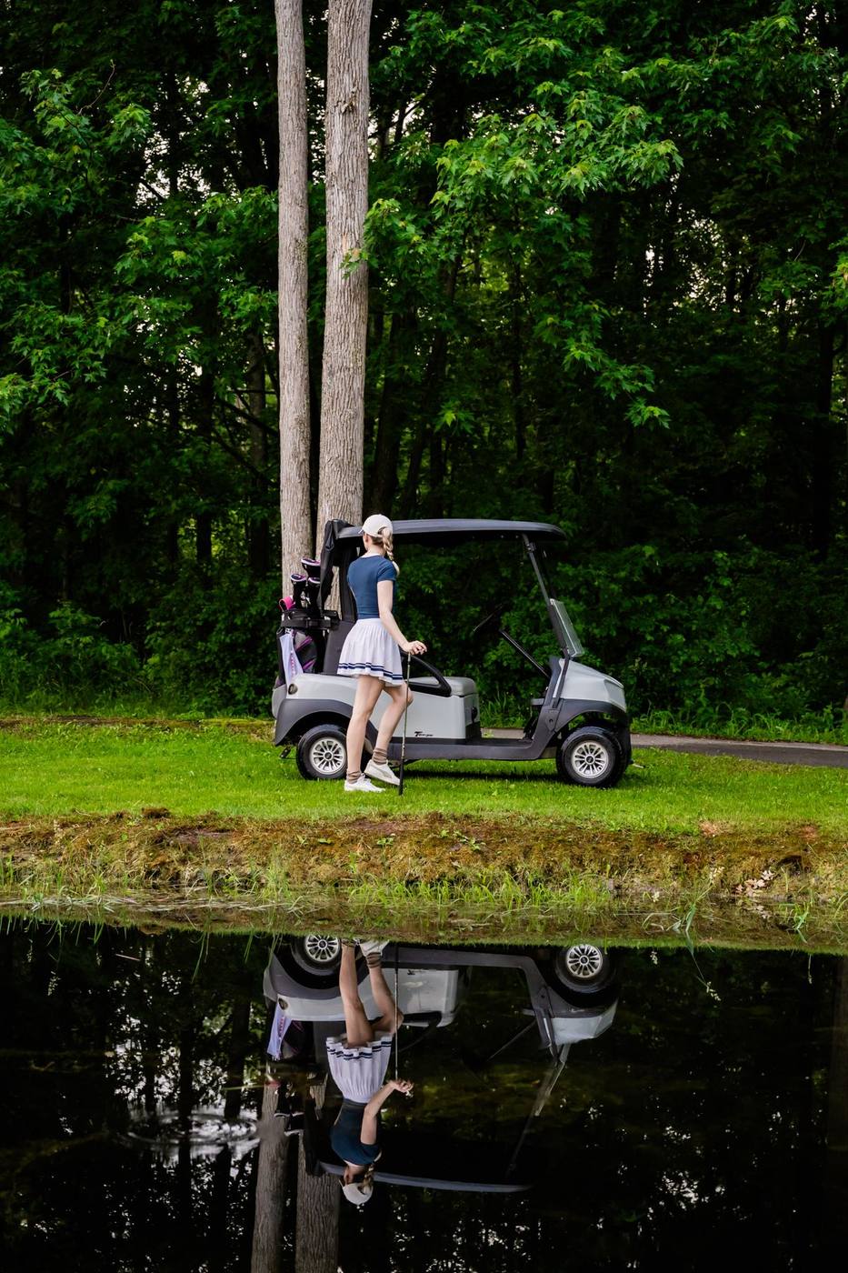 Golfer with a power cart beside the pond