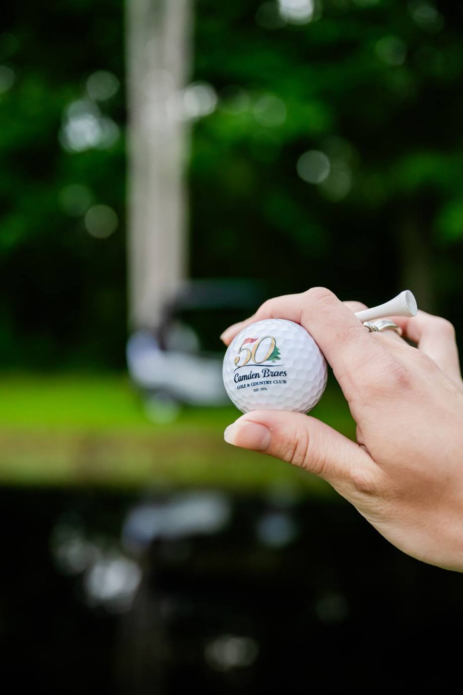 Hand holding a 50th anniversary Camden Braes golf ball