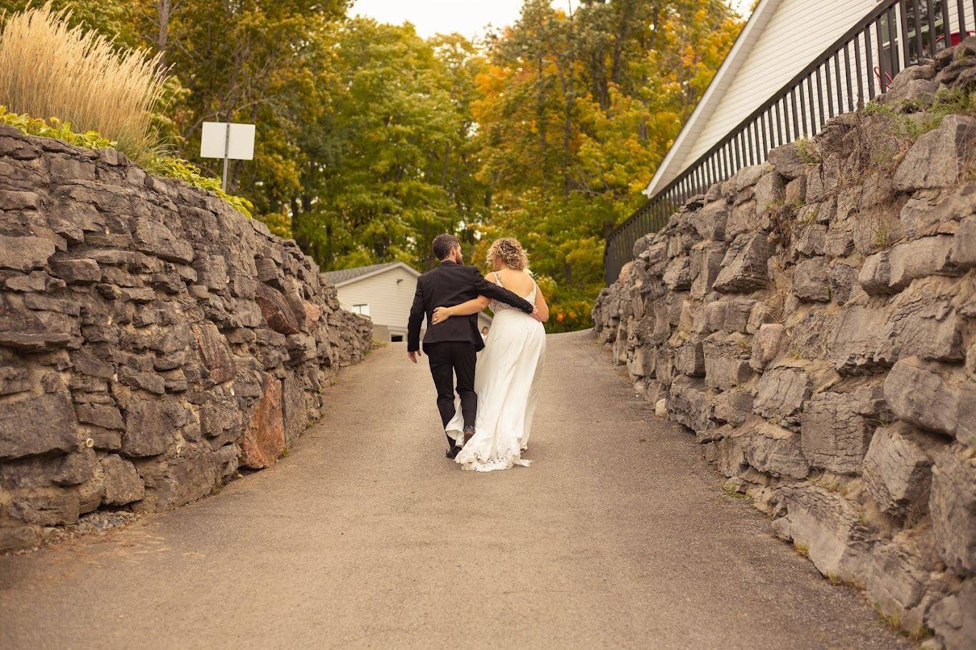 Newlyweds walking the stone wall path at Camden Braes