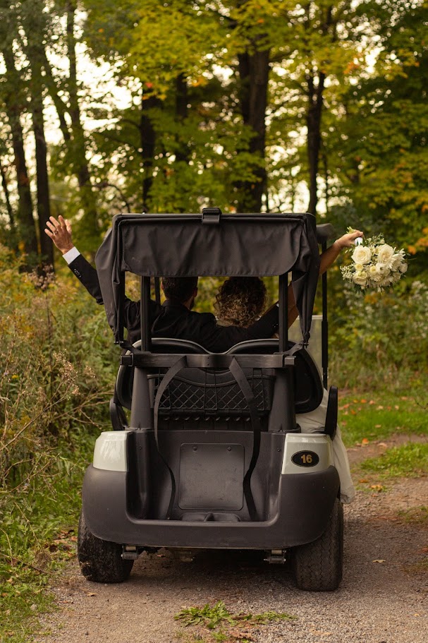Newlyweds waving from a golf cart