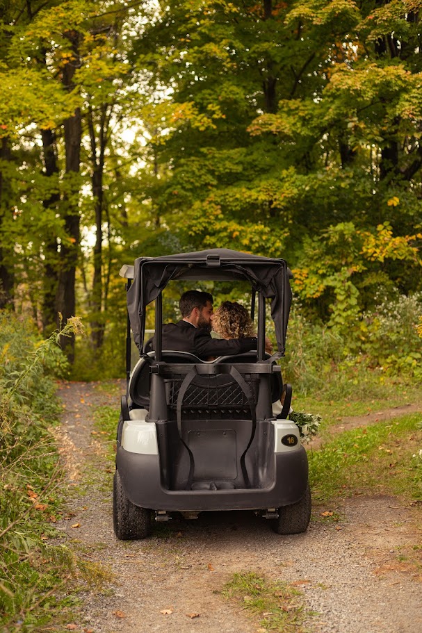 Newlyweds driving a golf cart down the wooded trail