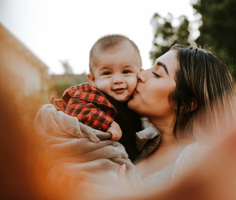 A mother kissing her smiling baby