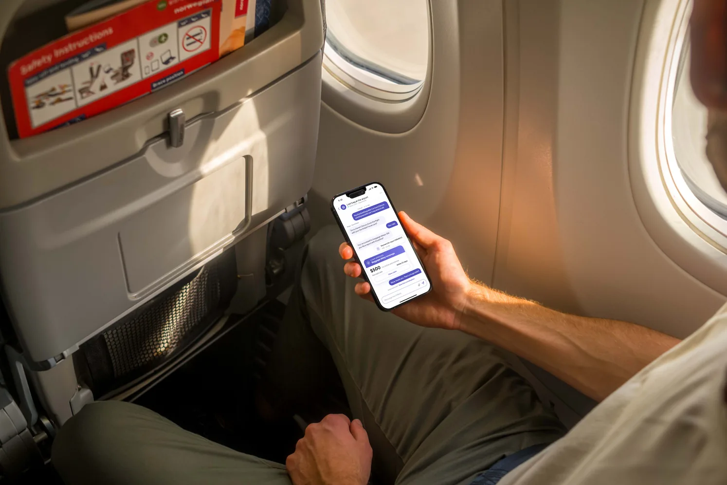 A traveler in a plane seat checking a baggage claim on his phone
