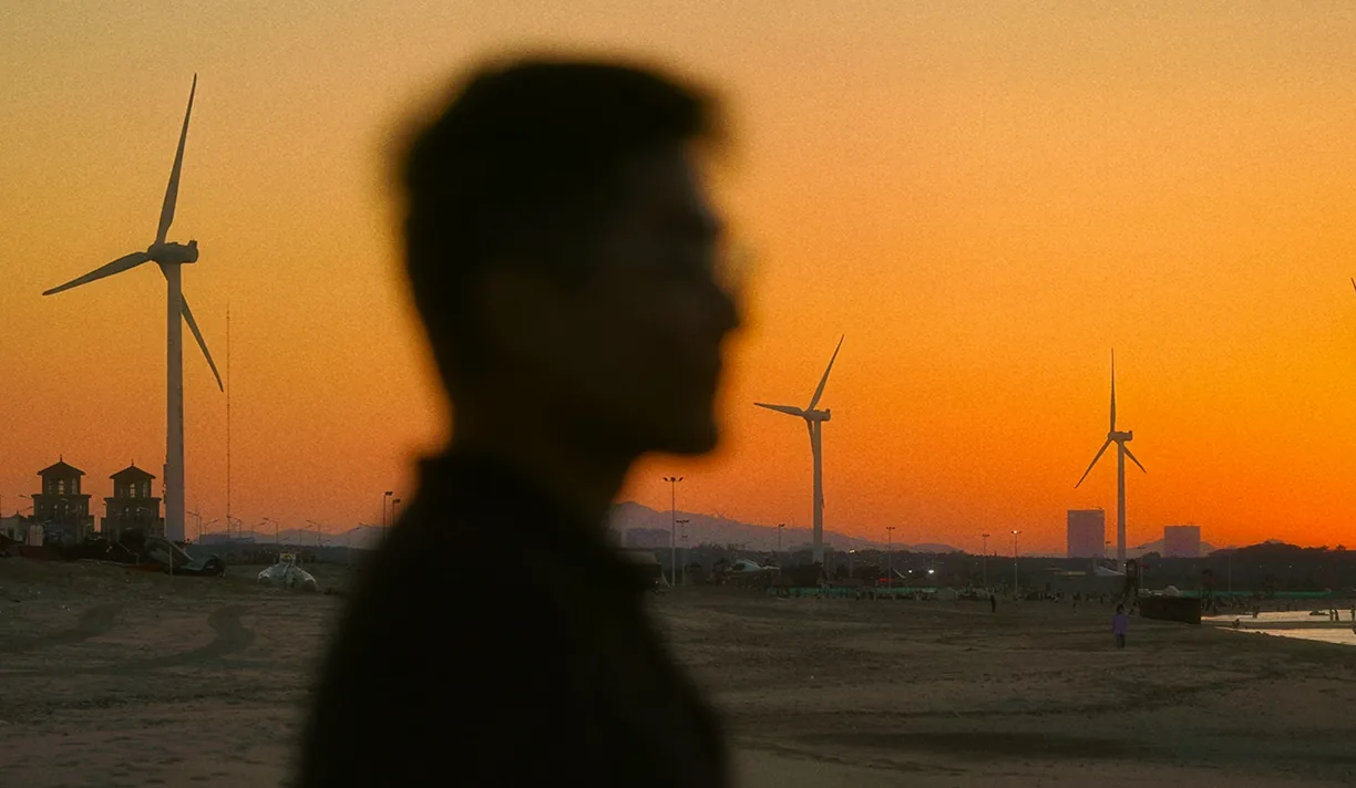 Silhouette of a person in front of wind turbines at sunset